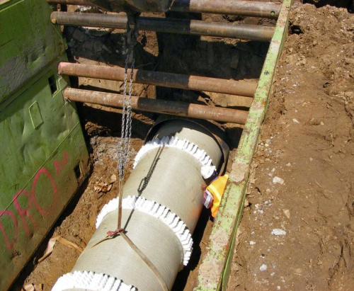 Stand-offs (white bands around the cylinder) allowed the pipe to be installed through existing iron drainage channels without having to excavate the channels.