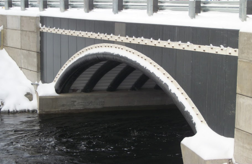 A bridge design featuring 12 concrete-filled FRP arch tubes on a 6ft rise and a composite headwall system as the end treatments replaced a deteriorated pipe culvert in the Jenkins Bridge in Bradley, Maine. The new FRP/concrete structure withstood the extreme hydraulic forces of an ice flow in its first year of service with no negative results. (Picture courtesy of AIT Bridges.)