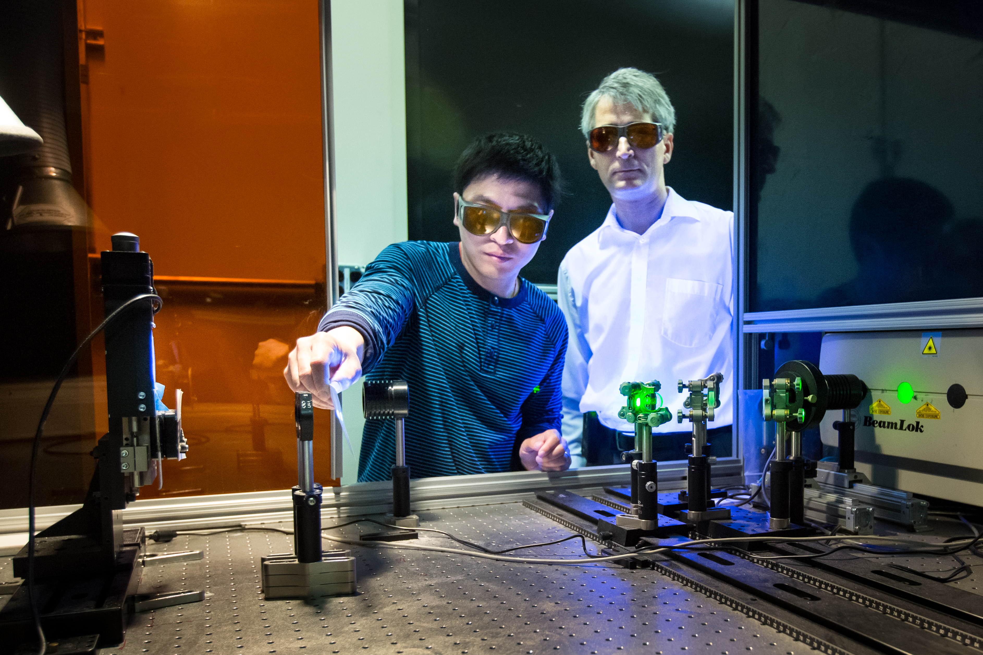 Adrian Sabau and Jian Chen work with a laser to prepare the surface of carbon fiber composites and aluminum.