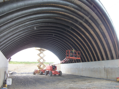 Plenty of room for heavy equipment under the 54 ft span concrete bridge in Caribou, Maine, built using 22 carbon/glass fibre inflatable arches as permanent formwork and concrete reinforcement. A construction and cost-saving advantage of the FRP components is that no such equipment is needed. (Picture courtesy of AIT Bridges.)